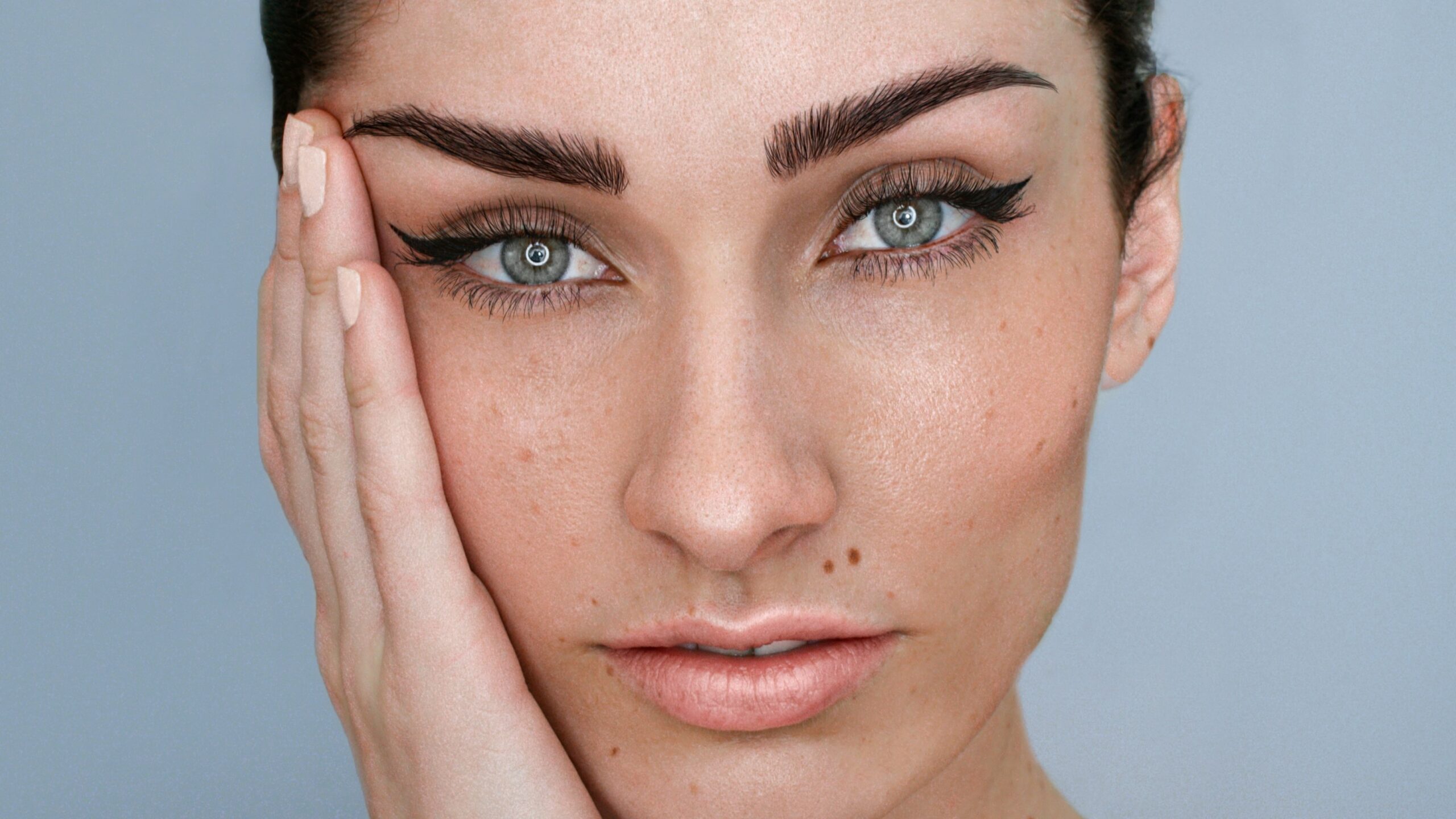Moters veido artimas vaizdas su microblading antakiais ir natūraliu makiažu, tamsūs plaukai surišti