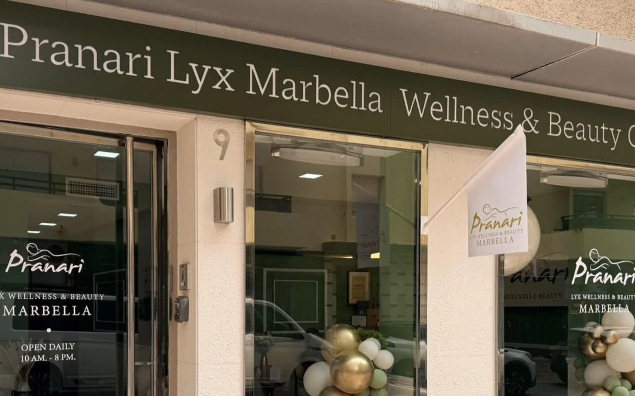 Anchan Massage vieta Marbella mieste, sveikatingumo ir grožio studija žaliu fasadu su baltais ir auksiniais balionais prie stiklinio įėjimo.
