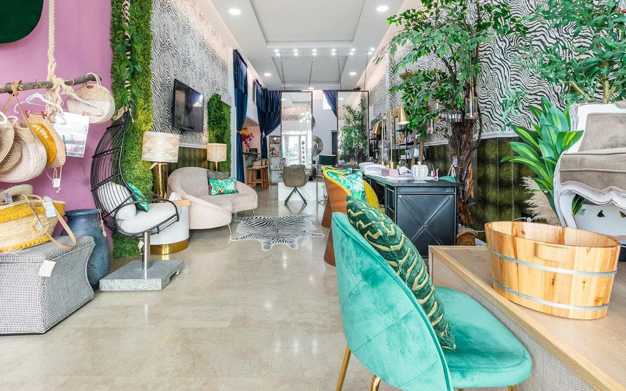 Brazilian Beauty Marbella interjeras, šviesus salonas su zebro rašto sienomis, žalia augalų siena, tirkizinėmis aksominėmis kėdėmis ir medine pedikiūro vonele.