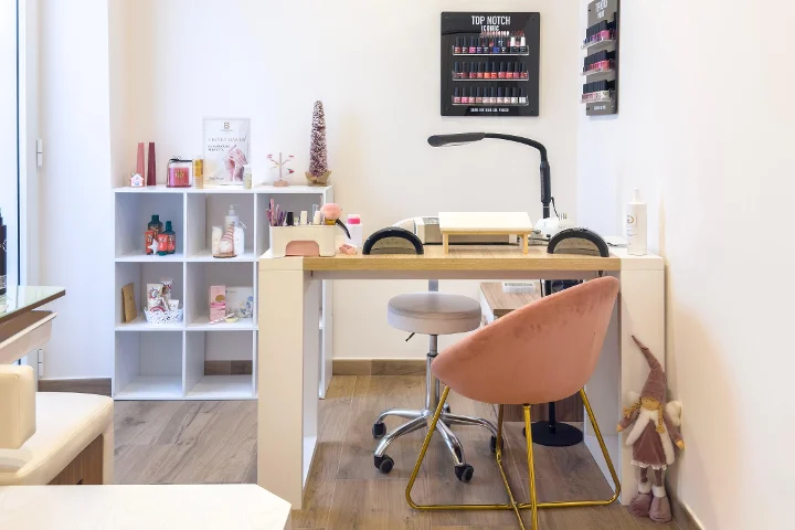 Manikiūro vieta Gd Beauty Clinc di Giulia Delogu salone Alghero su rožine aksomine kėde ir Top Notch nagų lakų ekspozicija.
