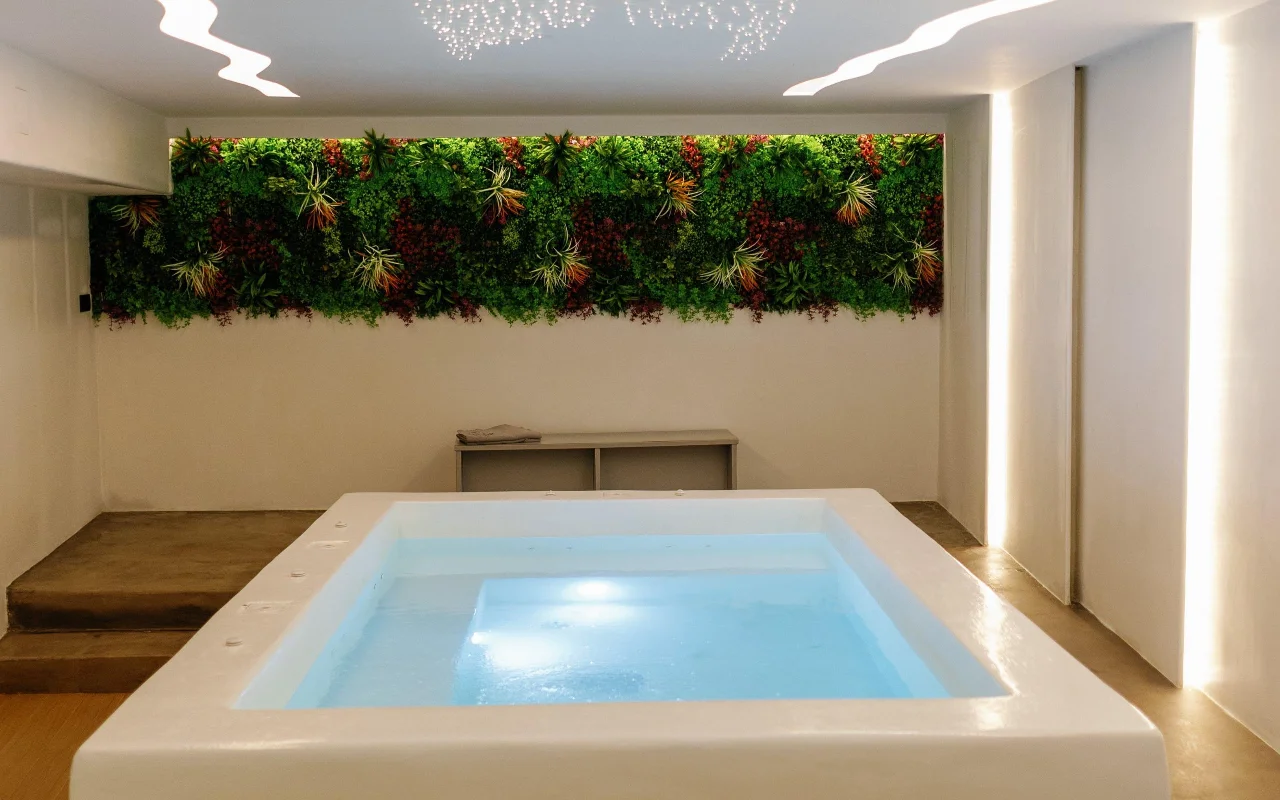 Liana Spa Therapy hidroterapijos baseinas Nakse, švelniai apšviestas iš vidaus, po spalvinga žalia stabilizuotų augalų siena ir lubomis, nusėtomis mažytėmis žvaigždučių šviesomis.