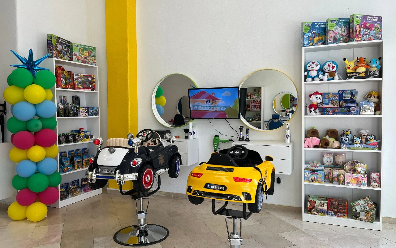 Peluplay vaikų kampelis Benalmádena mieste, kur formavimo kėdės yra žaislinių automobiliukų formos, su lentynomis, pilnomis animacinių herojų, apvaliais veidrodžiais ir balionų kolona.