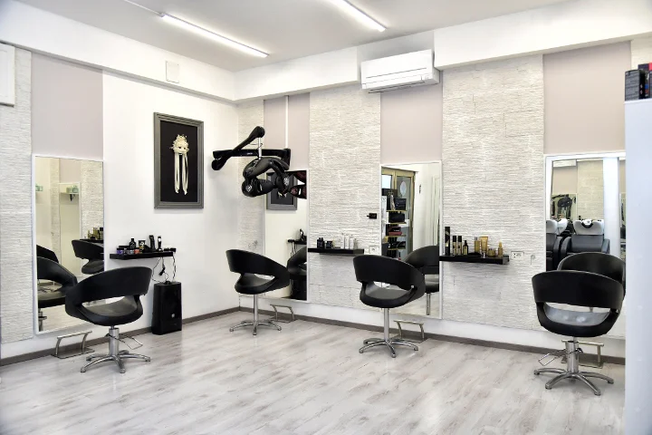 Modernios styling vietos Sp Beauty di Serena Pinna salone netoli Pittulongu paplūdimių Olbia mieste, su juodomis kėdėmis ir dideliais veidrodžiais.