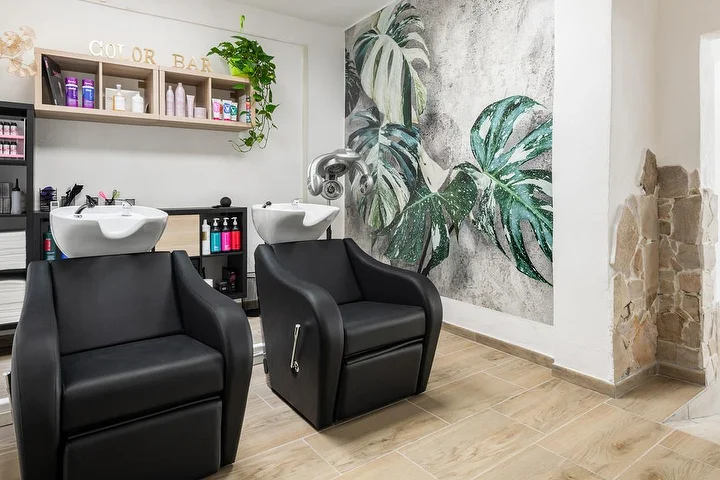 Plovimo kėdės ir color bar Yourself salone Tortolì su tropinių monstera lapų sienine tapyba.
